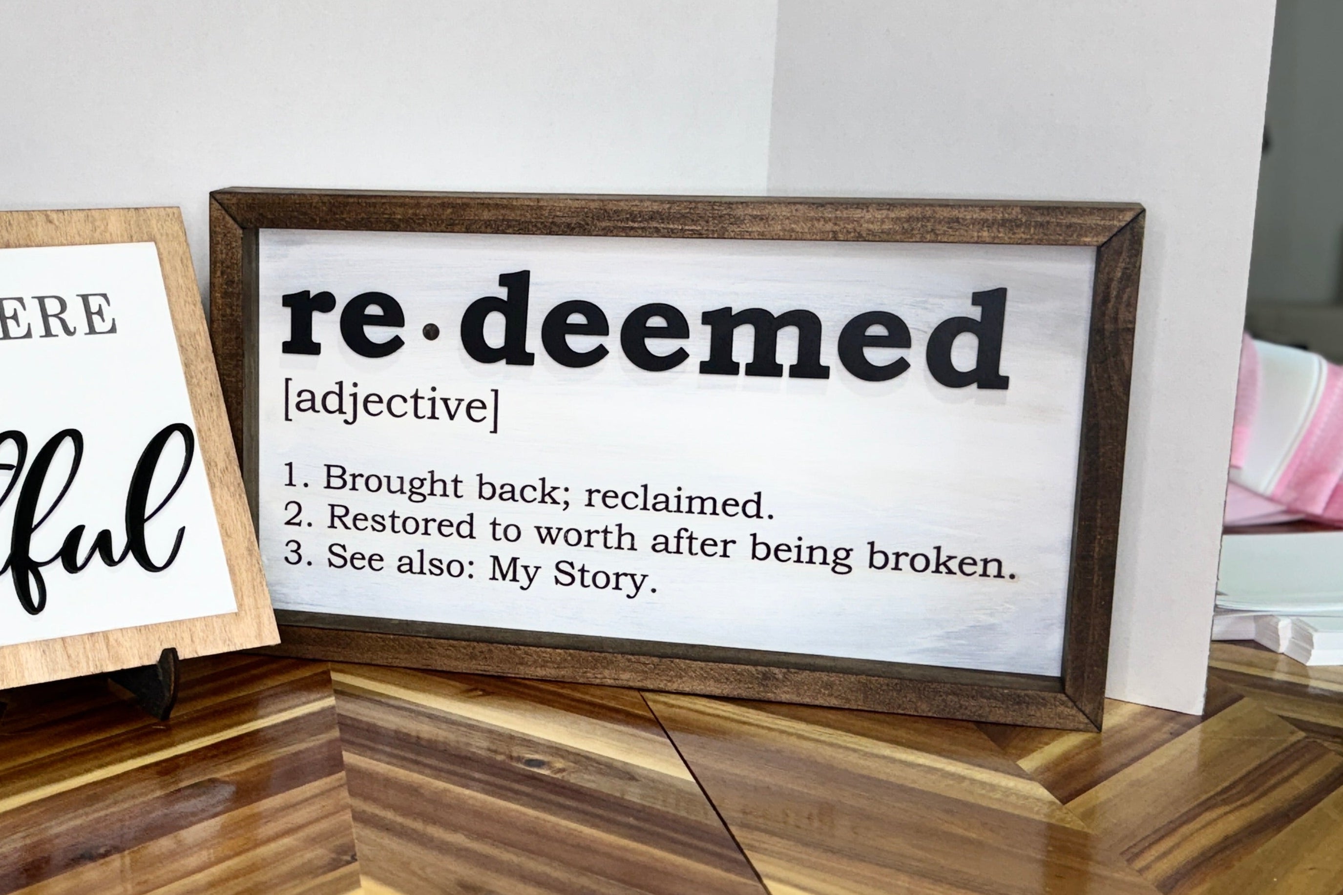 Two wooden signs with motivational phrases on a wooden surface.